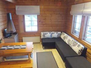 A cabin interior with a sofa, a table, and a lamp. - Vacation home Aili by Interhome (Padasjoki)