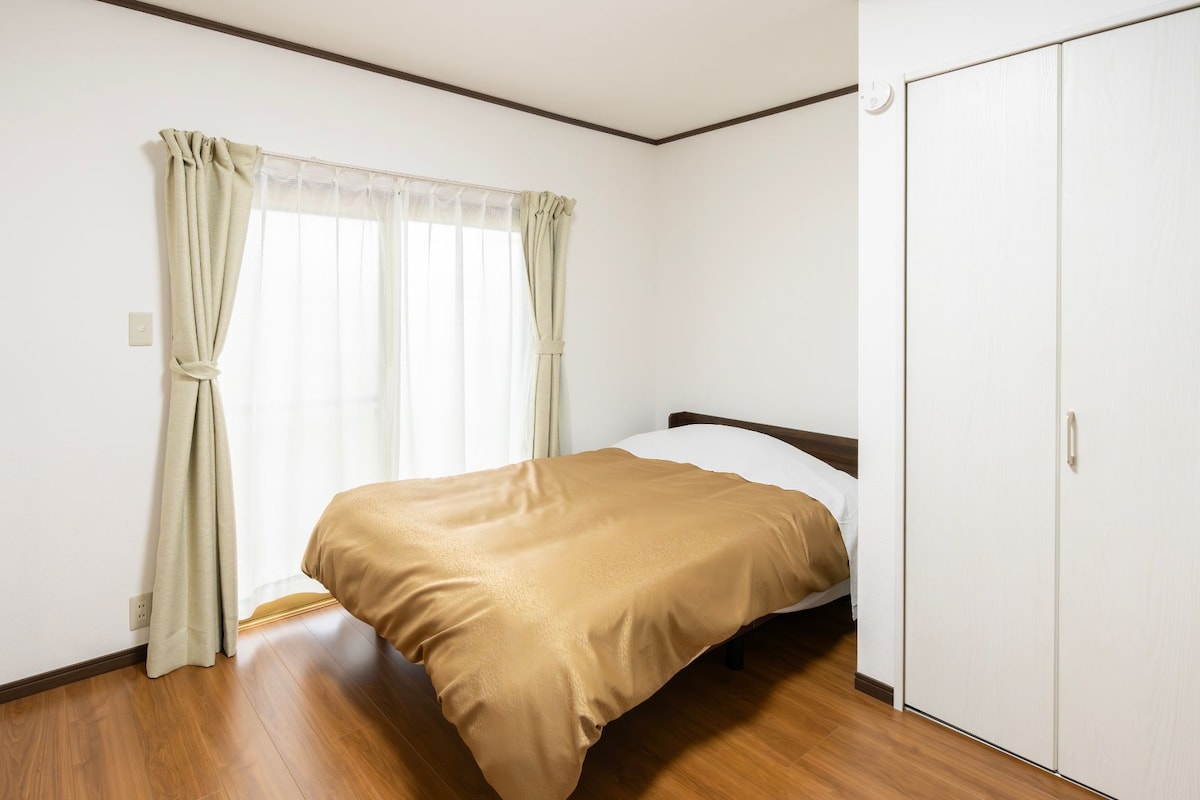 A bedroom with a bed, a wardrobe, and a window with curtains.