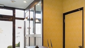 A reception desk with a telephone, a small table, and a window with a view of the outside. - Business Hotel Nishine (Hachimantai)