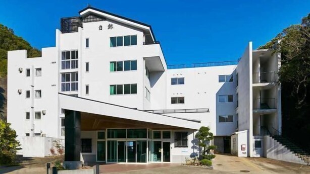 A modern building with a flat roof, multiple windows, and a prominent entrance with glass doors. - Isana no Yado Hakugei (Taiji)