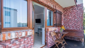 A brick exterior with a wooden deck, a table with chairs, and a bench. - Nostalgia by Interhome (Mielno)