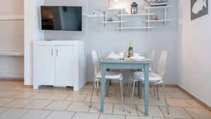 A modern dining area with a table set for two, a television above the table, and decorative items on shelves. - Nostalgia by Interhome (Mielno)
