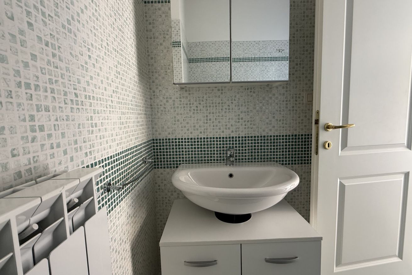 A bathroom with a white sink, a mirror, and a tiled backsplash.