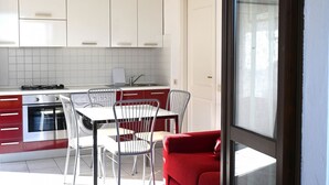 Una cocina moderna con armarios blancos, una mesa de comedor con sillas y un sofá rojo.