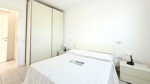 Habitación de hotel con cama, mesita de noche, lámpara, armario y puerta.