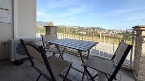 Un balcón con mesa y sillas, vista a un puente y un edificio al fondo.