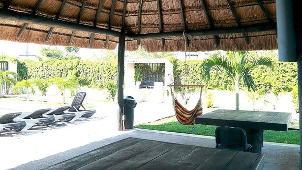 An outdoor seating area with a thatched roof, a hammock, and a bench. - In Playa del Carmen, Mexico (Playa del Carmen)