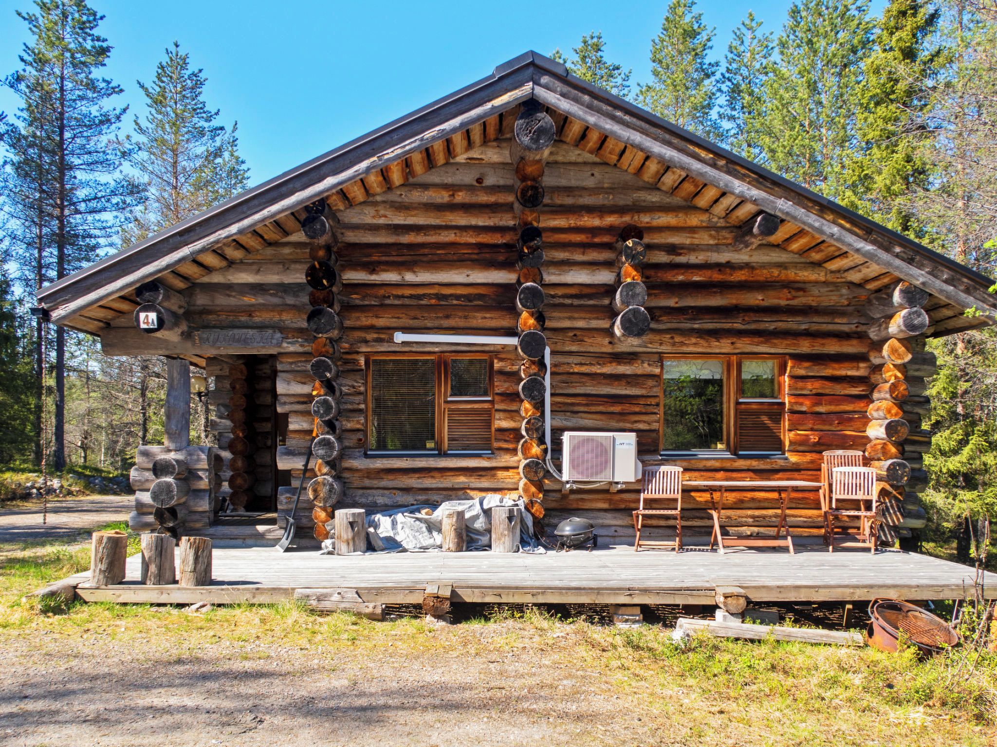 A log cabin with a porch, a fireplace, and a window.