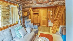 A log cabin interior with a sofa, a wooden door, and a window with curtains.