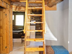 A wooden interior with a ladder leading to a loft area, a bed, and a small table. - Rukaveska 4a by Interhome (Kuusamo)