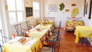 A dining area with multiple tables covered in yellow tablecloths, metal chairs, and a wooden floor. - Hostellerie Avances Soiree (Tateyama)