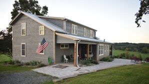 A two-story house with a covered porch, a flag, and a number '76' on the front.