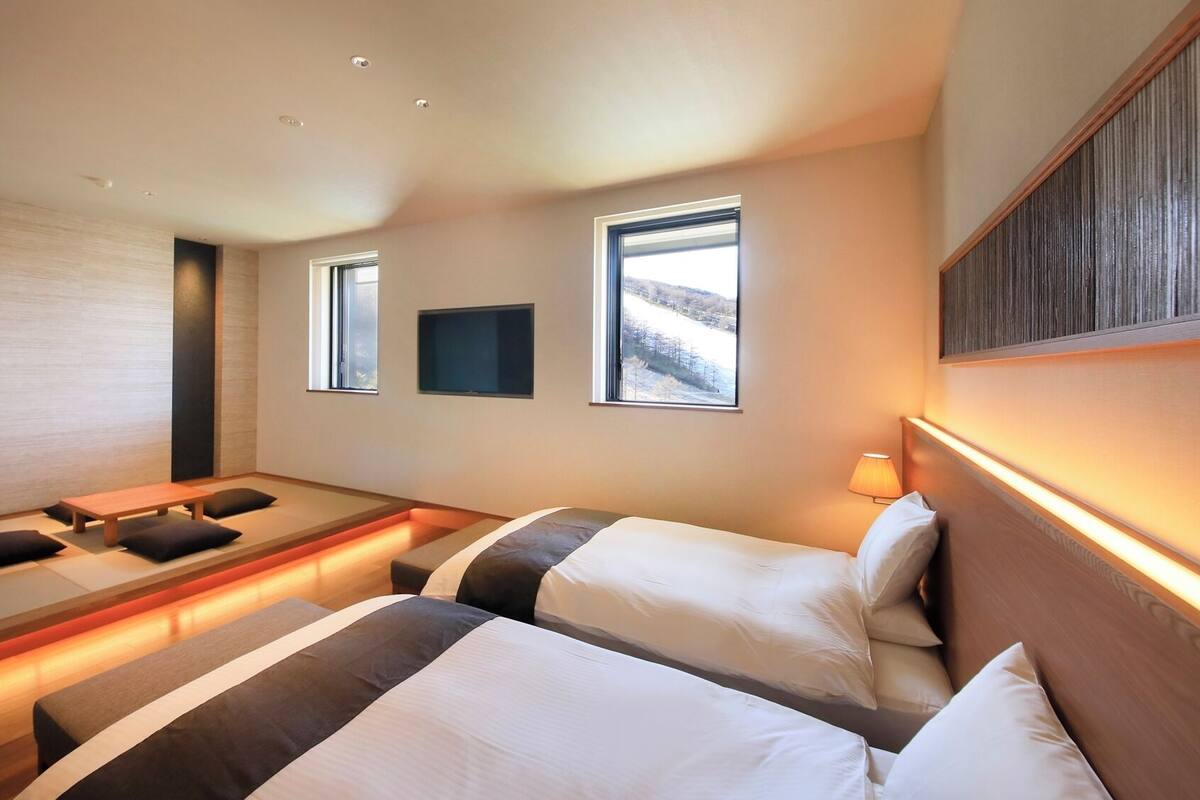 A hotel room with a bed, bedside tables, a TV, and a window with a view.