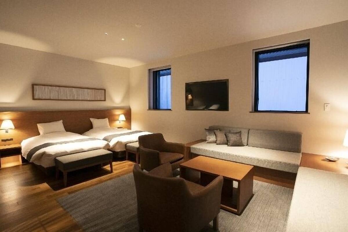 A hotel room with two beds, a sofa, a coffee table, and two chairs.