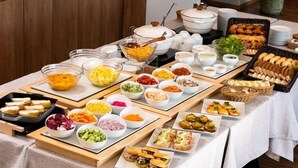 A buffet table with various food items and containers. - Takamine Mountain Hotel (Tsumagoi)
