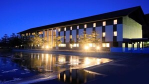 A modern building with a reflective pool in front. - Takamine Mountain Hotel (Tsumagoi)