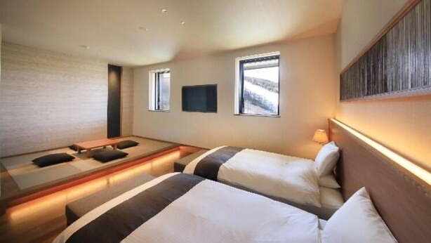A hotel room with two beds, a flat-screen TV, and a large window. - Takamine Mountain Hotel (Tsumagoi)