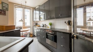 A modern kitchen with stainless steel appliances, a large island, and a view of the street through the window.