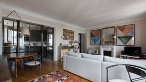 A modern living room with a sofa, chairs, a dining table, and a fireplace.