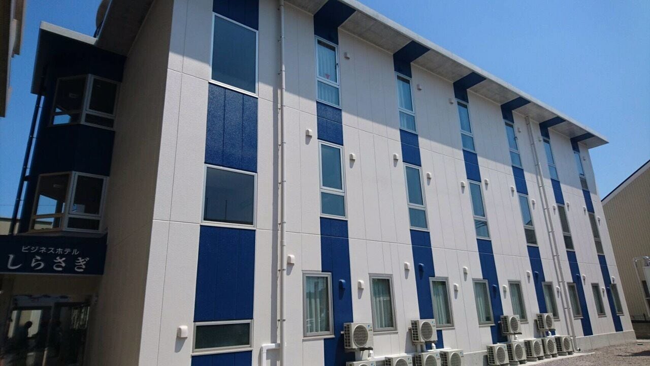 Un hotel de varios pisos con un diseño moderno, que presenta una serie de ventanas y unidades de aire acondicionado en la planta baja.
