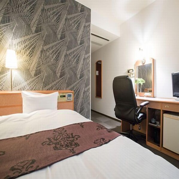 Una habitación de hotel con una cama, un escritorio con silla, una computadora y un espejo.