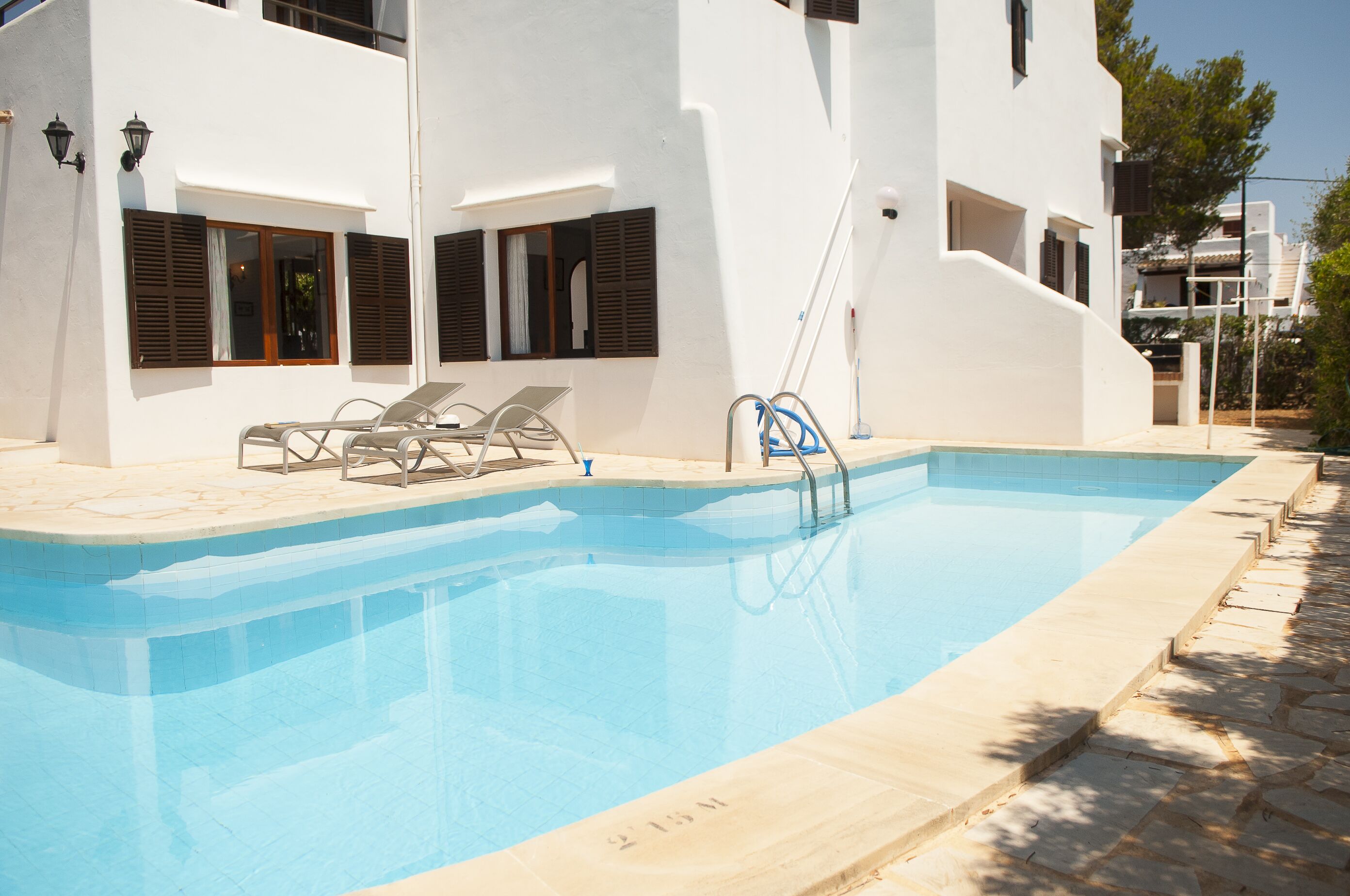 A swimming pool with lounge chairs and a hose.