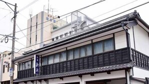A traditional Japanese building with a two-story structure, a covered entrance, and a small outdoor seating area. - Shinhama Ryokan (Yatsushiro)