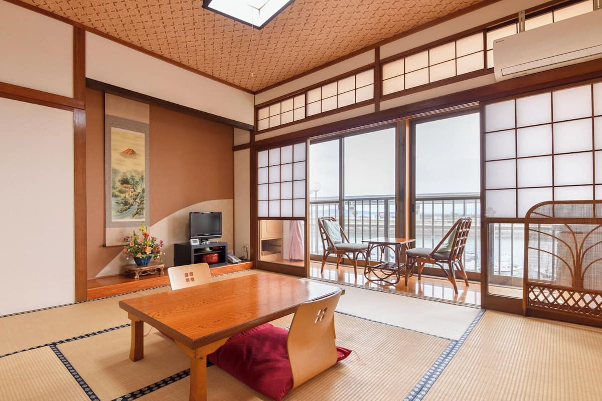 A traditional Japanese room with tatami flooring, a wooden table, and a view through shoji screens.