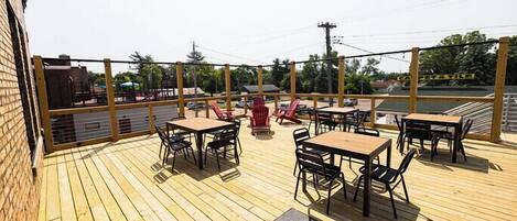Una terraza de madera con asientos exteriores y vista a la calle.