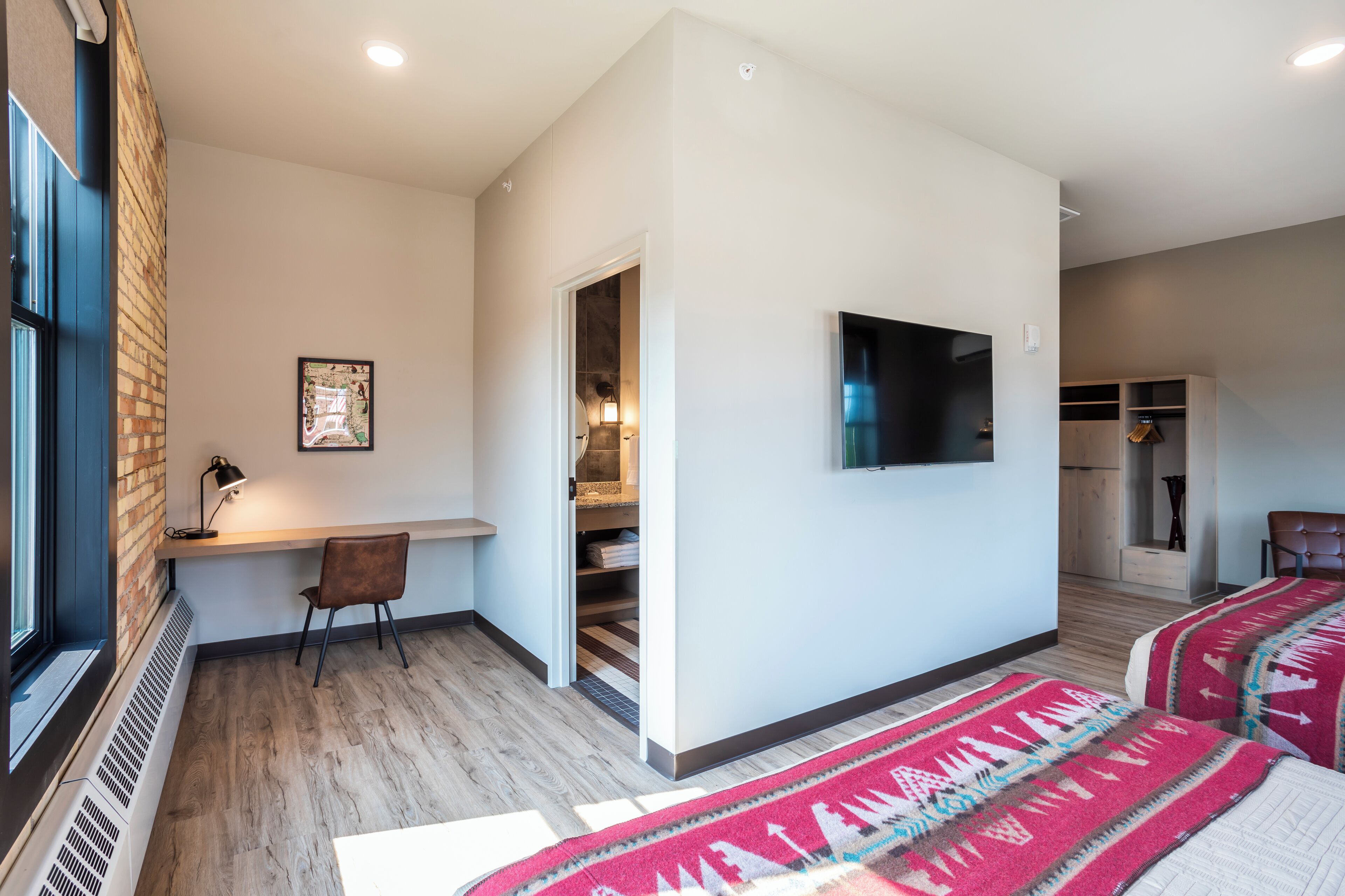 Una habitación de hotel moderna con una cama grande, un escritorio, una silla y un televisor.