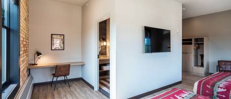 Una habitación de hotel moderna con una cama grande, un escritorio, una silla y un televisor.