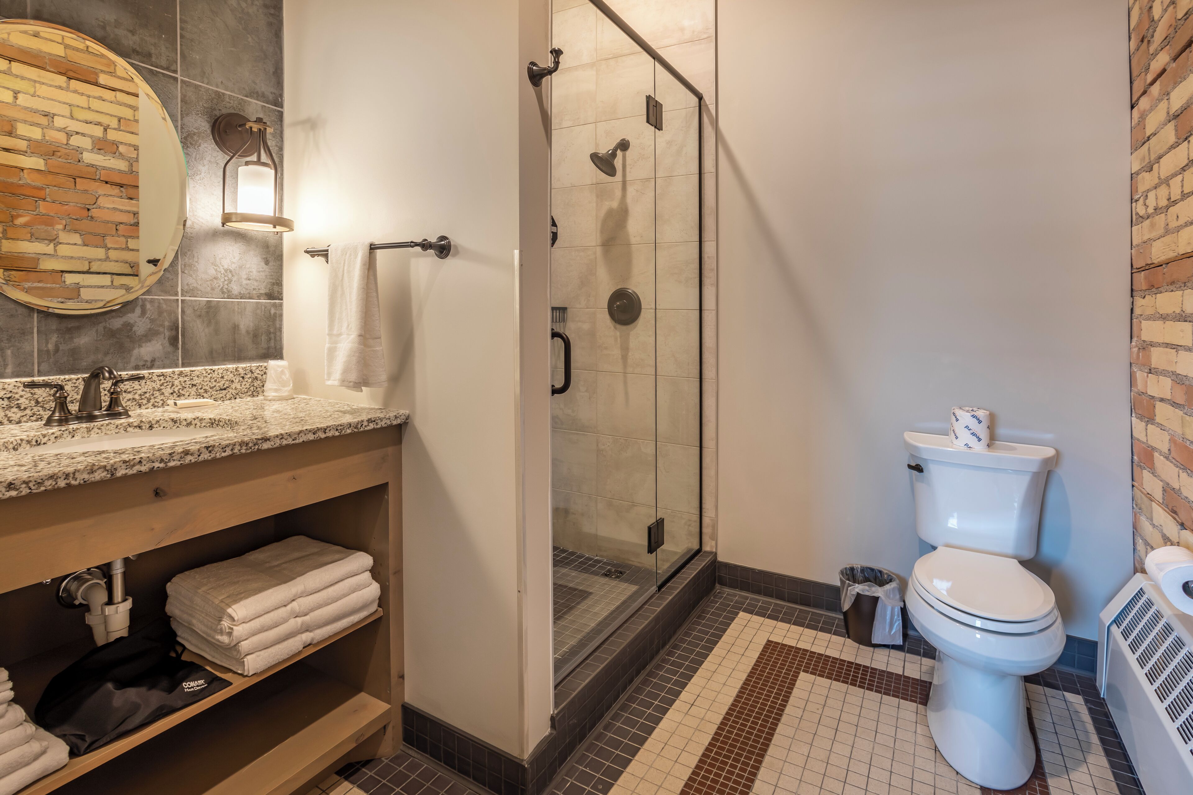 A bathroom with a granite countertop sink, a glass-enclosed shower, and a toilet.