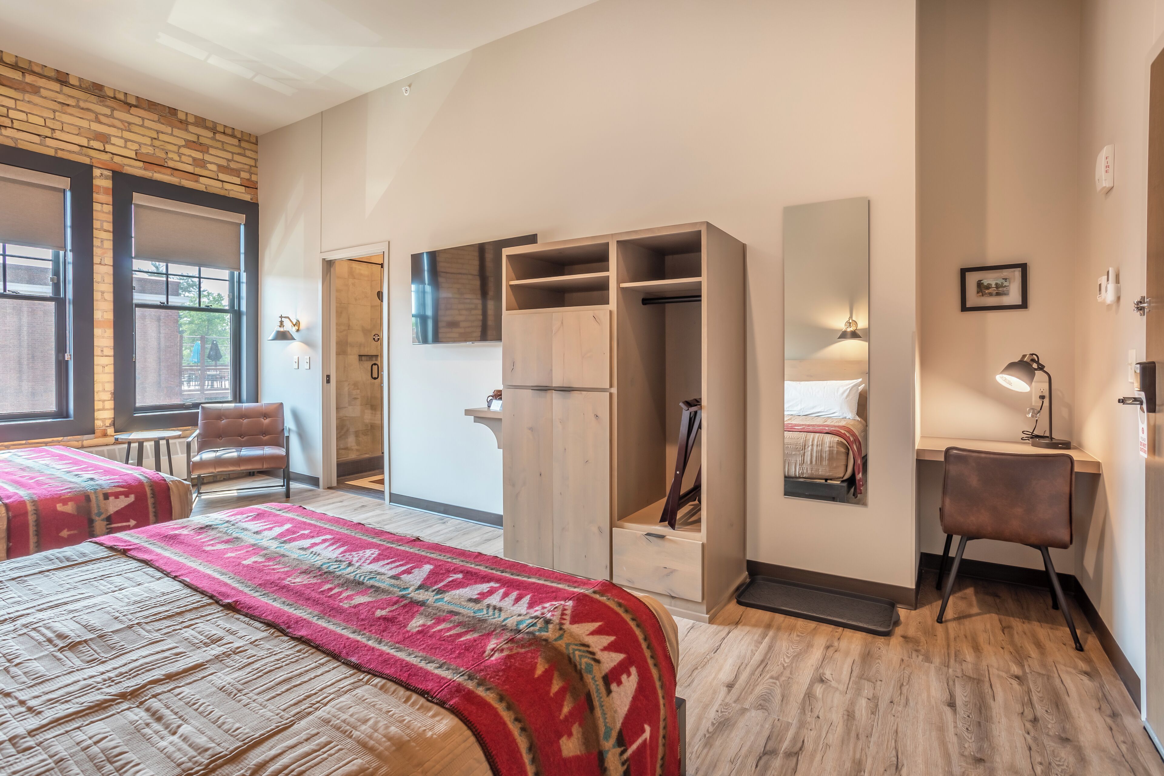 A bedroom with a bed, a wardrobe, a desk, and a chair.