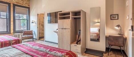 A bedroom with a bed, a wardrobe, a desk, and a chair.