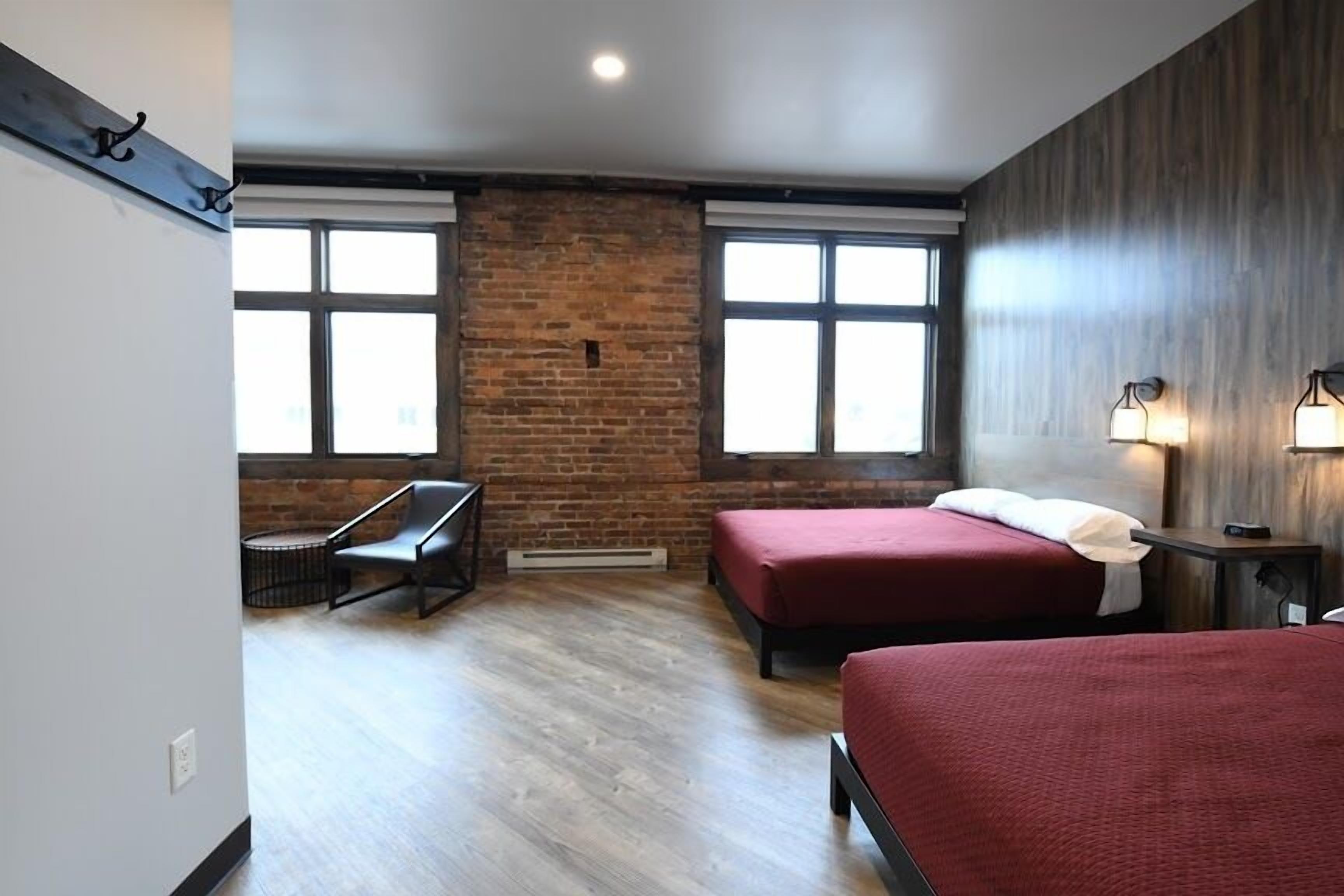 A hotel room with two beds, a desk, and a chair.