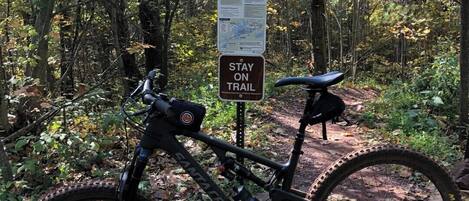 Ein Mountainbike steht neben einem Wegweiser in bewaldetem Gelände.