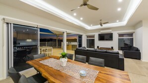 Un salón moderno con una mesa de comedor de madera, sofá de cuero negro y ventiladores de techo.
