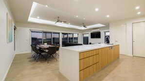 Una cocina moderna con una isla central, zona de comedor con sillas y un ventanal con vistas.