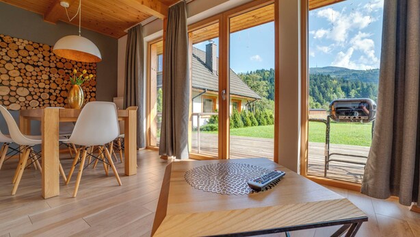 A modern dining area with a wooden table, chairs, and a view of a mountain landscape through large windows. - Chaty Pod Beskidkiem by Interhome (Szczyrk)