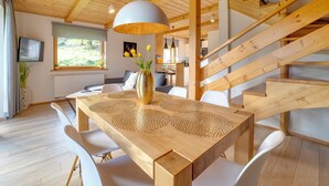 A modern interior with a wooden dining table, white chairs, a staircase, and a large window. - Chaty Pod Beskidkiem by Interhome (Szczyrk)