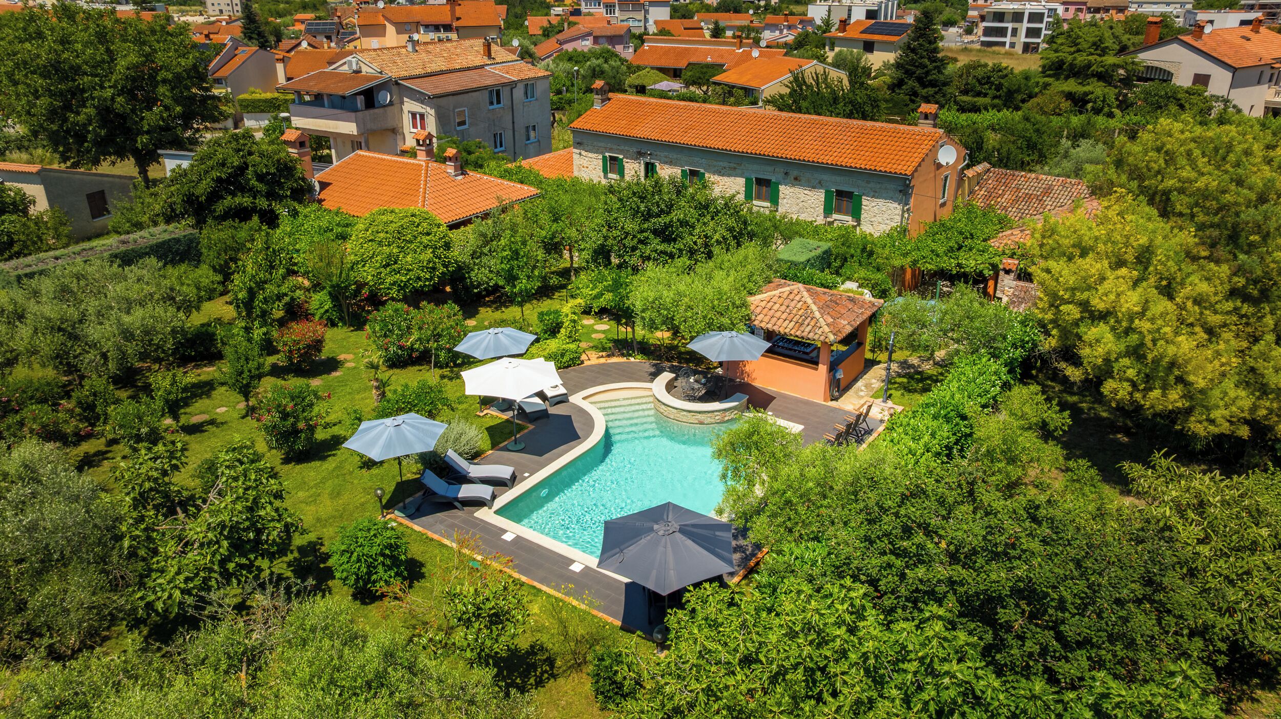 A residential area with a swimming pool surrounded by greenery and a few buildings.