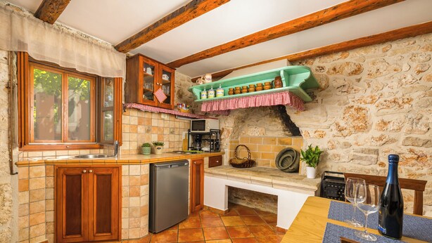 A rustic kitchen with a wooden countertop, a built-in oven, and a stone wall. - Authentic Istrian House - Apartment with saltwater pool- 15 min from Kamenjak (Pula)