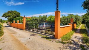 A gated driveway leading to a building with a metal gate and orange walls. - Authentic Istrian House - Apartment with saltwater pool- 15 min from Kamenjak (Pula)