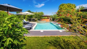 A swimming pool with lounge chairs and umbrellas, surrounded by greenery and a gazebo. - Authentic Istrian House - Apartment with saltwater pool- 15 min from Kamenjak (Pula)