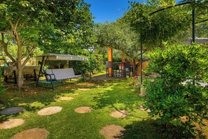 Een tuin met een bankje, een pergola en een pad.