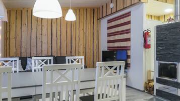 Una habitación con pared de madera, un sofá blanco, una televisión y una chimenea.