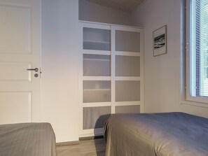 A bedroom with a bed, a wardrobe, and a window with blinds.