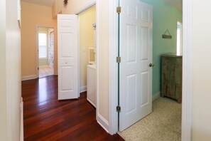 A hallway with wooden flooring, white doors, and a beige carpet. - Home with golf cart,community pool,Spinnakers Reach community (Emerald Isle)