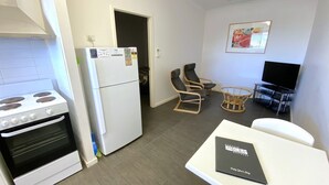 Eine kompakte Küche mit Herd, Kühlschrank und einer Essecke mit Stühlen und Tisch.
