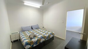 Ein Schlafzimmer mit Bett, Nachttisch und einer Tür, die auf einen Balkon führt.